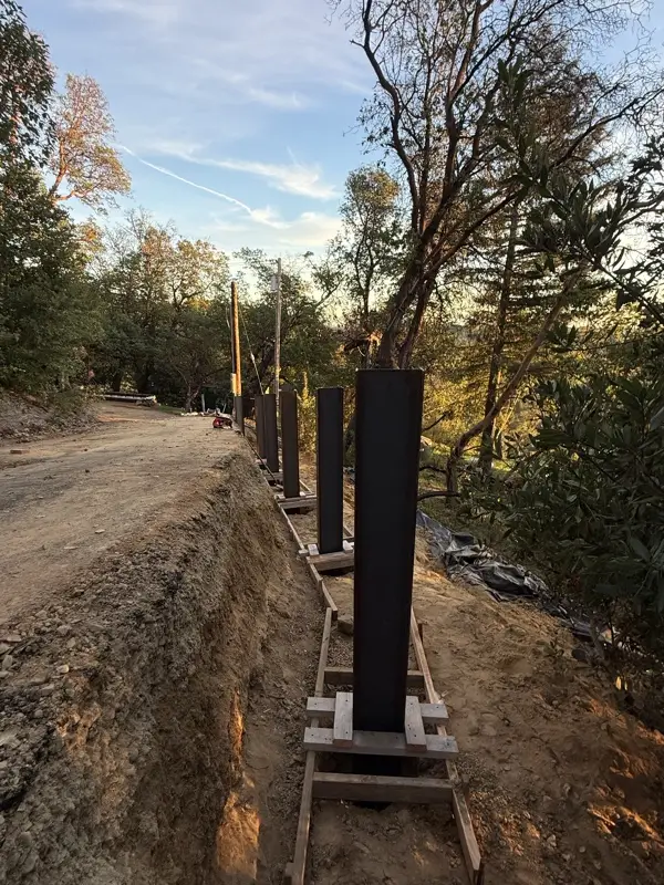 Excavated slope with steel I-beam posts set in concrete