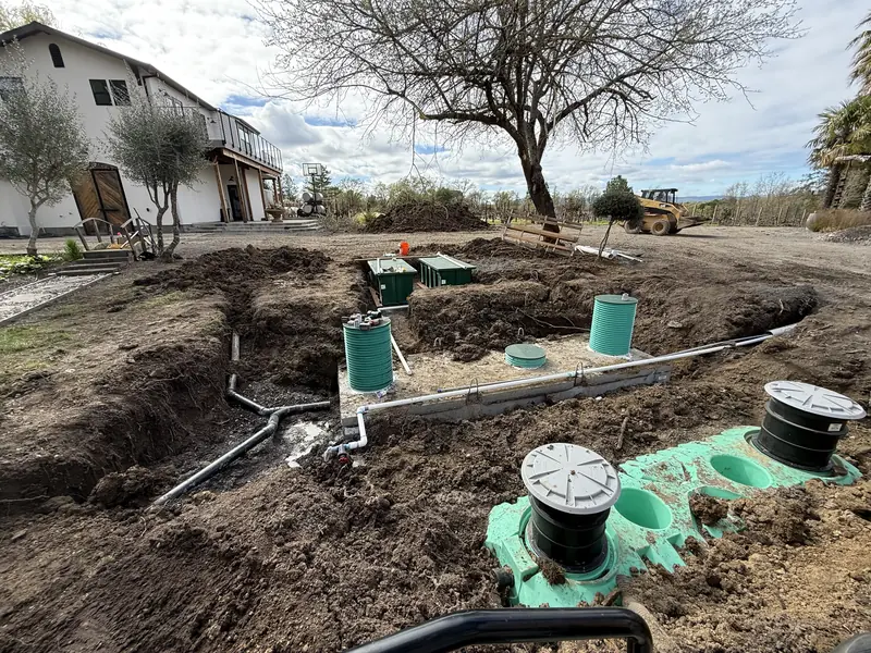 Complex multi tank septic system installed at a residential property with the home behind